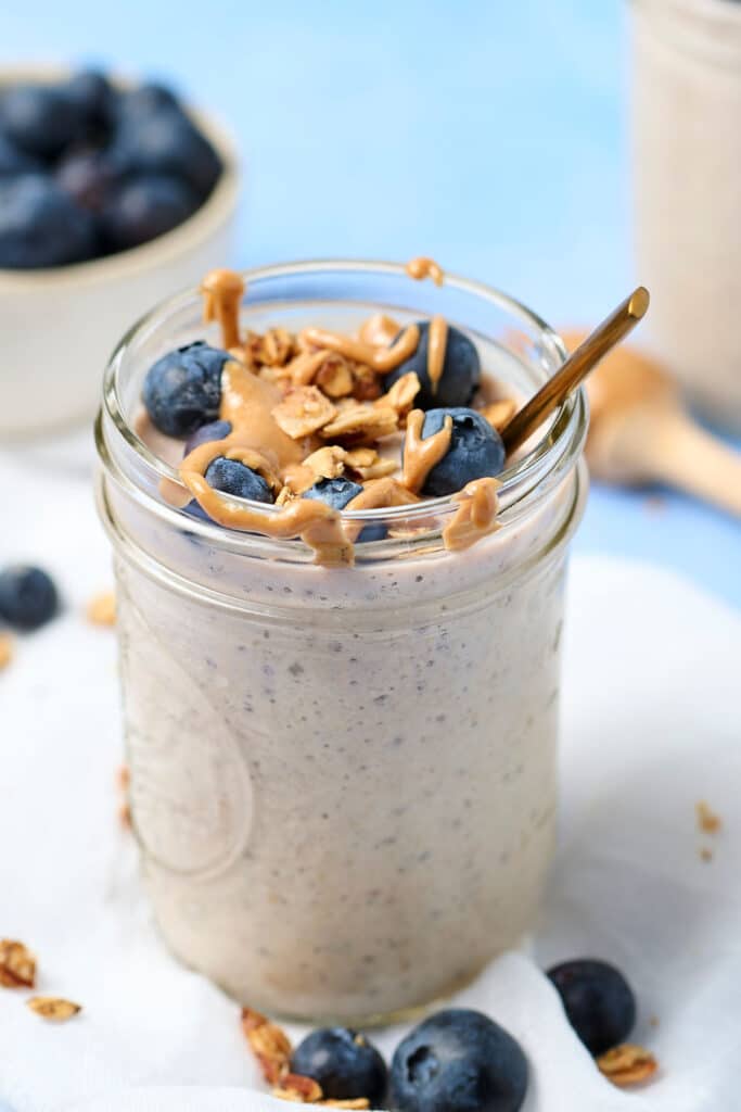 blended overnight oats in a mason jar with blueberries and nut butter drizzle.