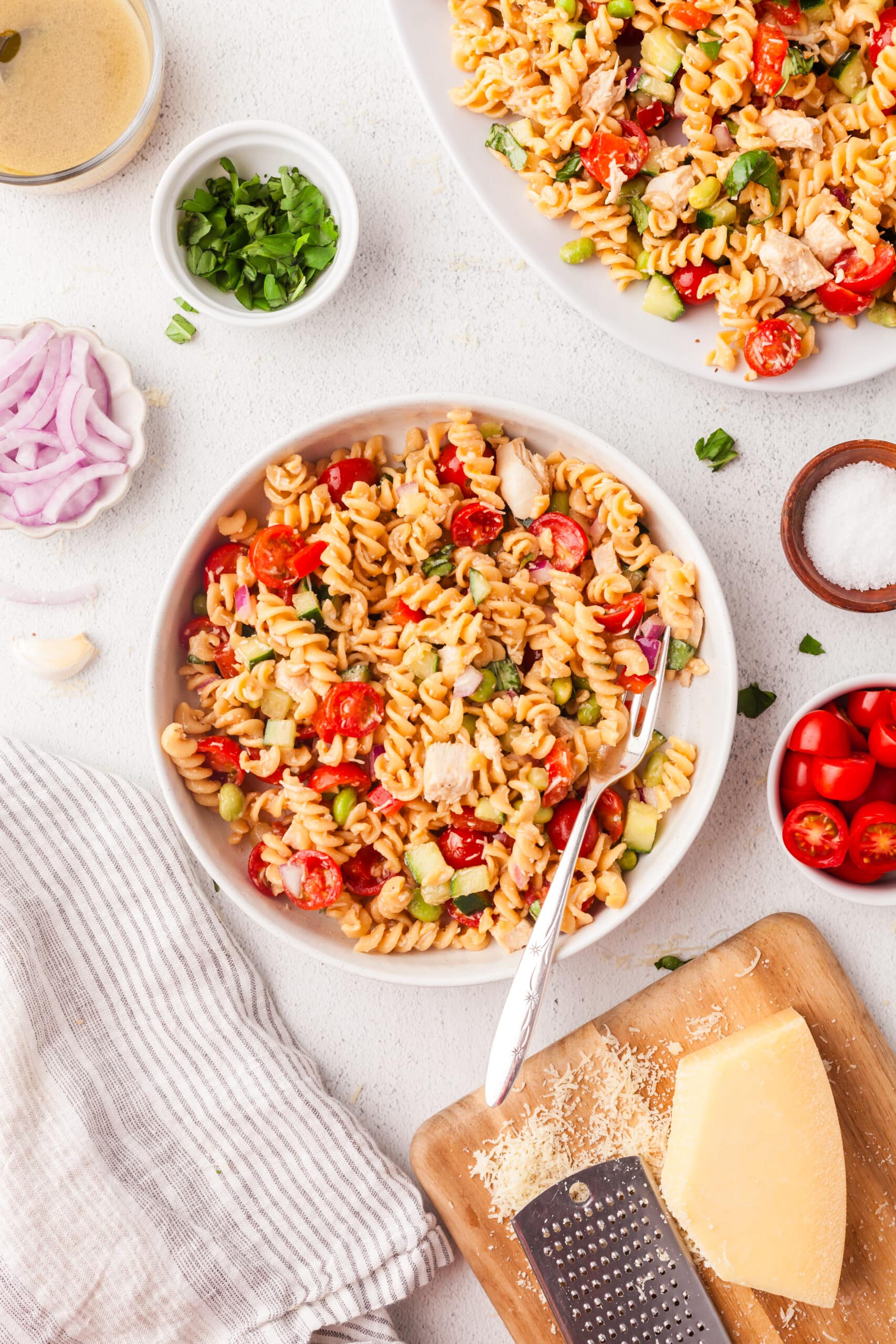 colorful protein pasta salad in white bowl with serving spoon in it.