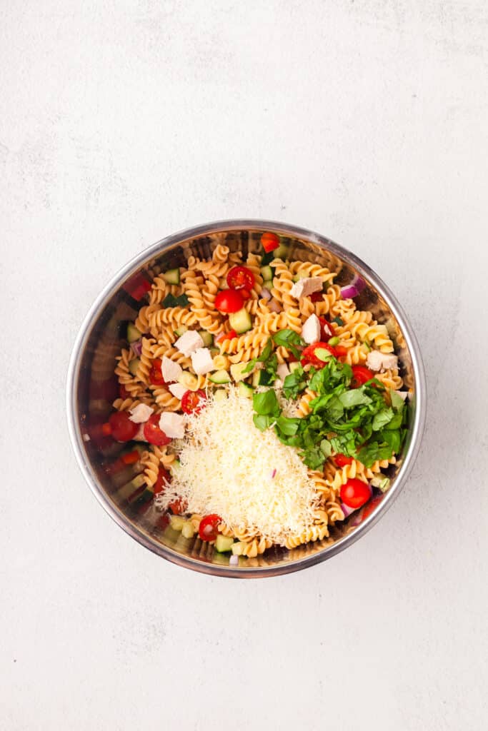making a high protein pasta salad in a large mixing bowl.