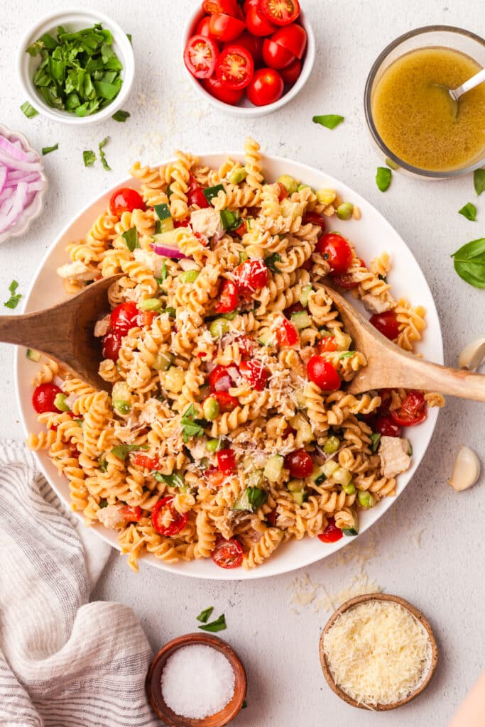 high protein pasta salad on a large white plate with wooden serving utensils.