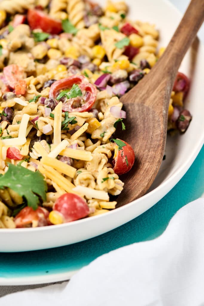 closeup view of wooden spoon scooping into taco pasta salad.