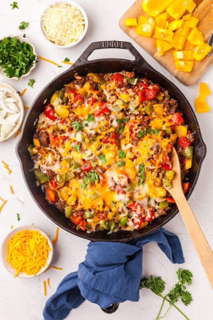 unstuffed peppers in a cast iron skillet on countertop with ingredients surrounding it.
