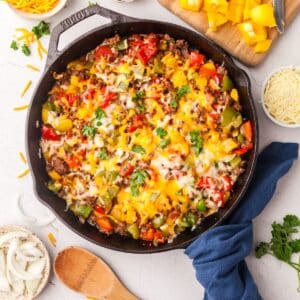 unstuffed peppers in a cast iron skillet on countertop with ingredients surrounding it.