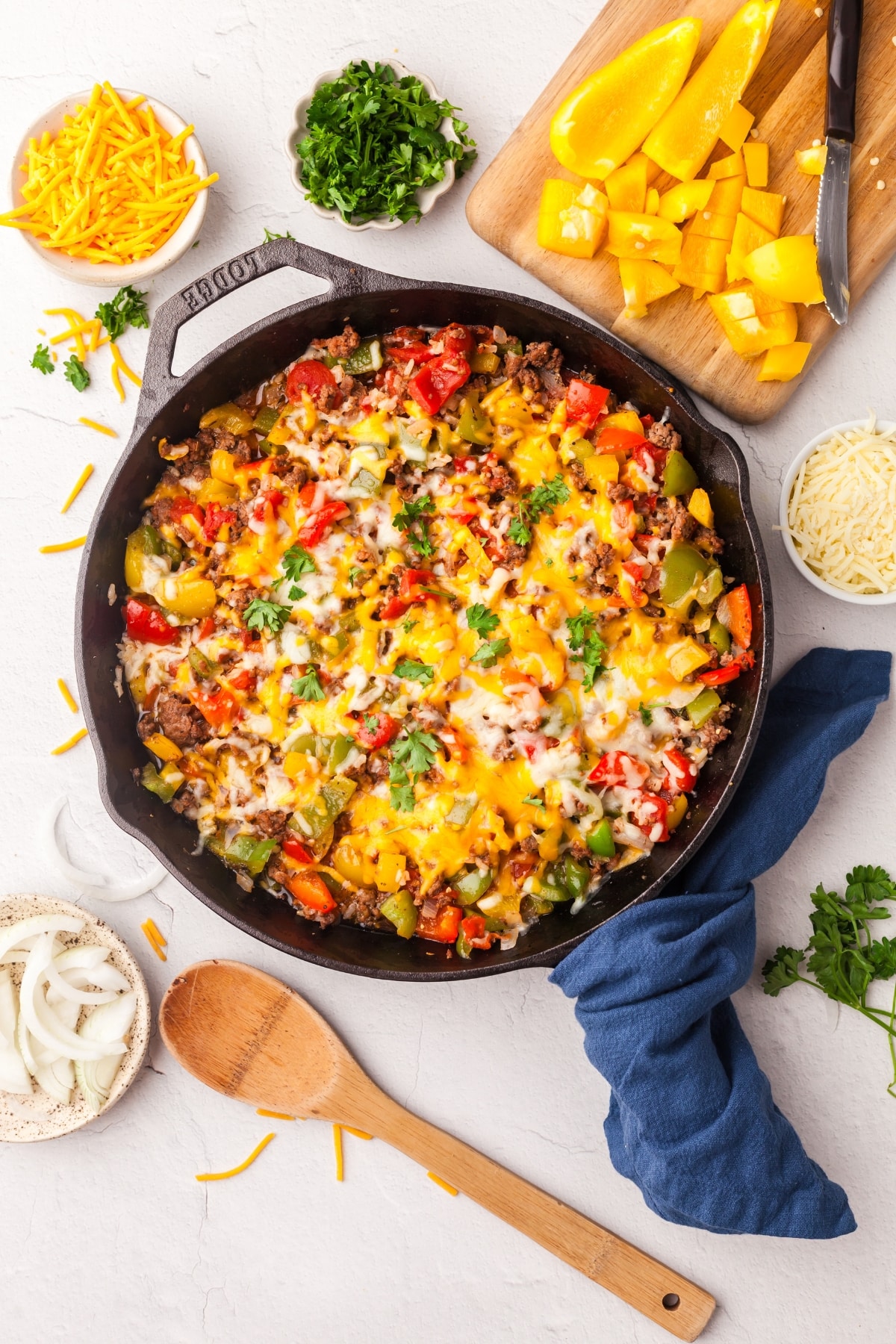 unstuffed peppers in a cast iron skillet on countertop with ingredients surrounding it.