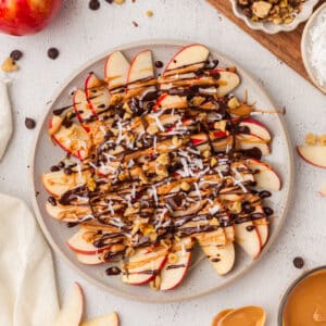 overview shot of apple nachos slices on a white plate.