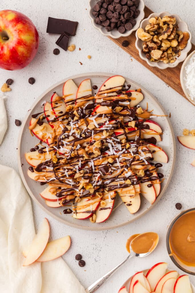 overview shot of apple nachos slices on a white plate.