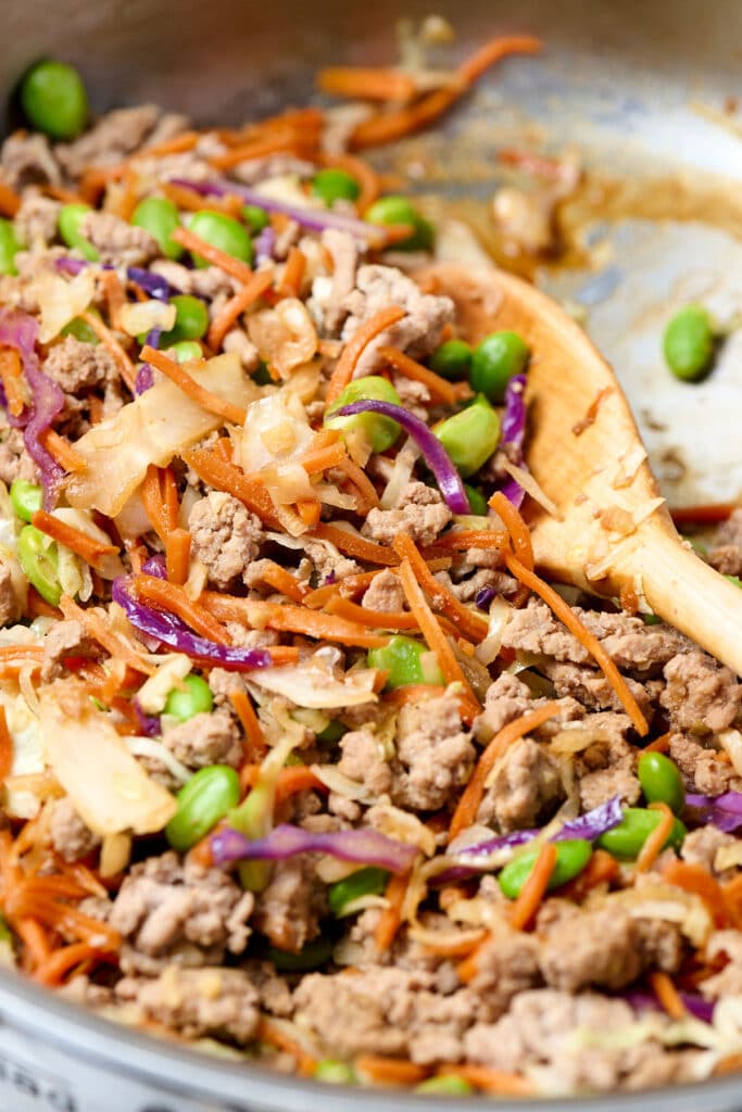 egg roll ground turkey bowls with soba noodles in a skillet with wooden spoon.