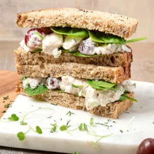 pcos chicken salad sandwich halves stacked on a cutting board.