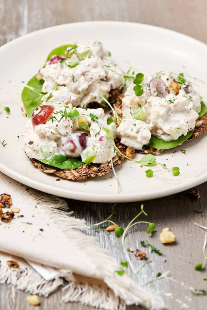 pcos chicken salad on seed crackers on a plate.