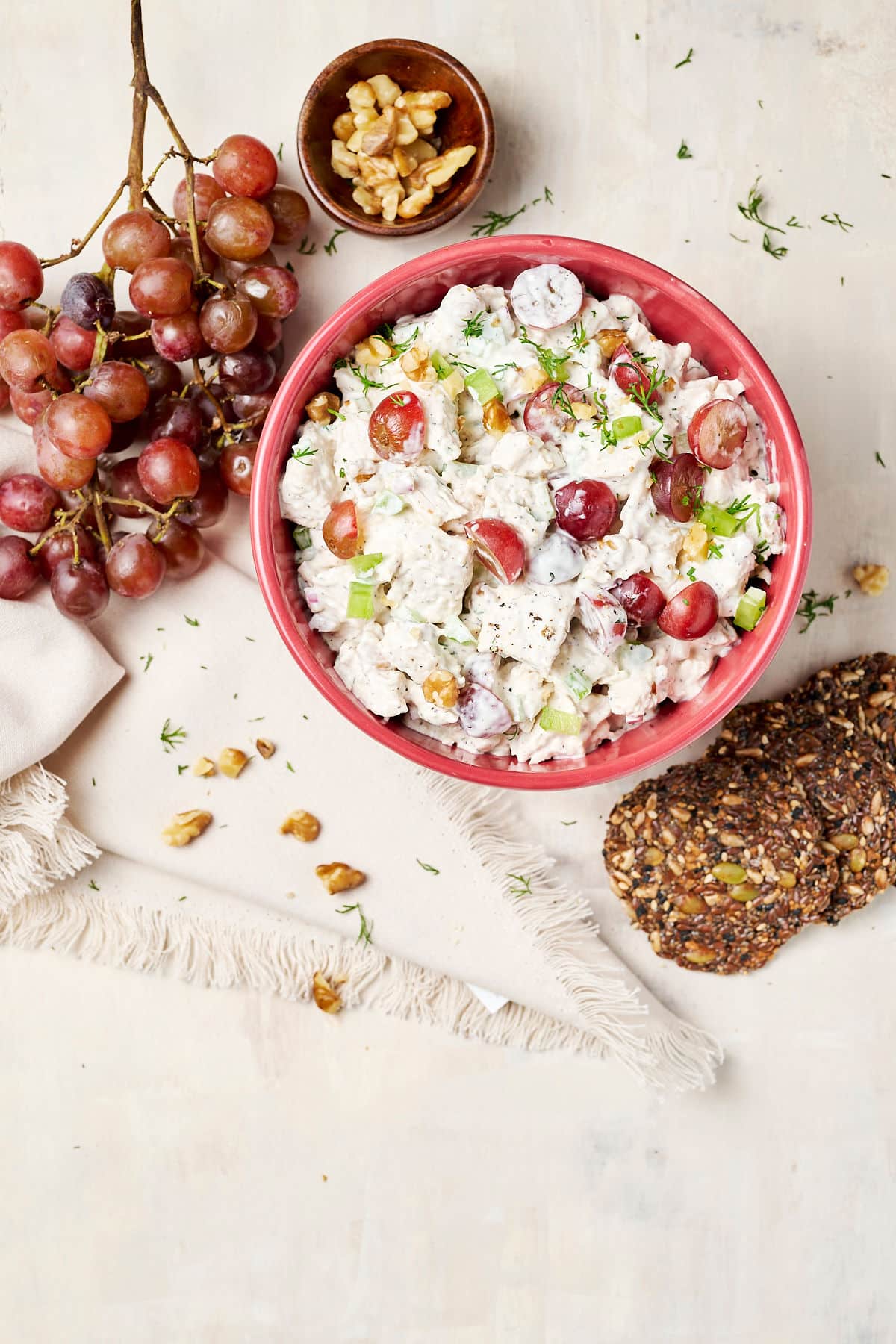 pcos friendly chicken salad in a bowl with grapes and seed crackers next to it.