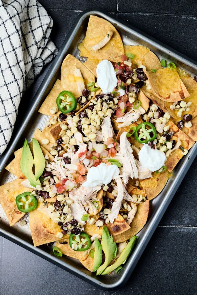 cilantro lime chicken on nachos with corn, beans, avocado, jalapenos, and sour cream.