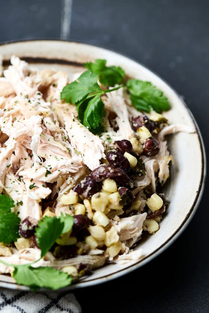 cilantro lime chicken with beans and corn in a bowl with fresh cilantro.