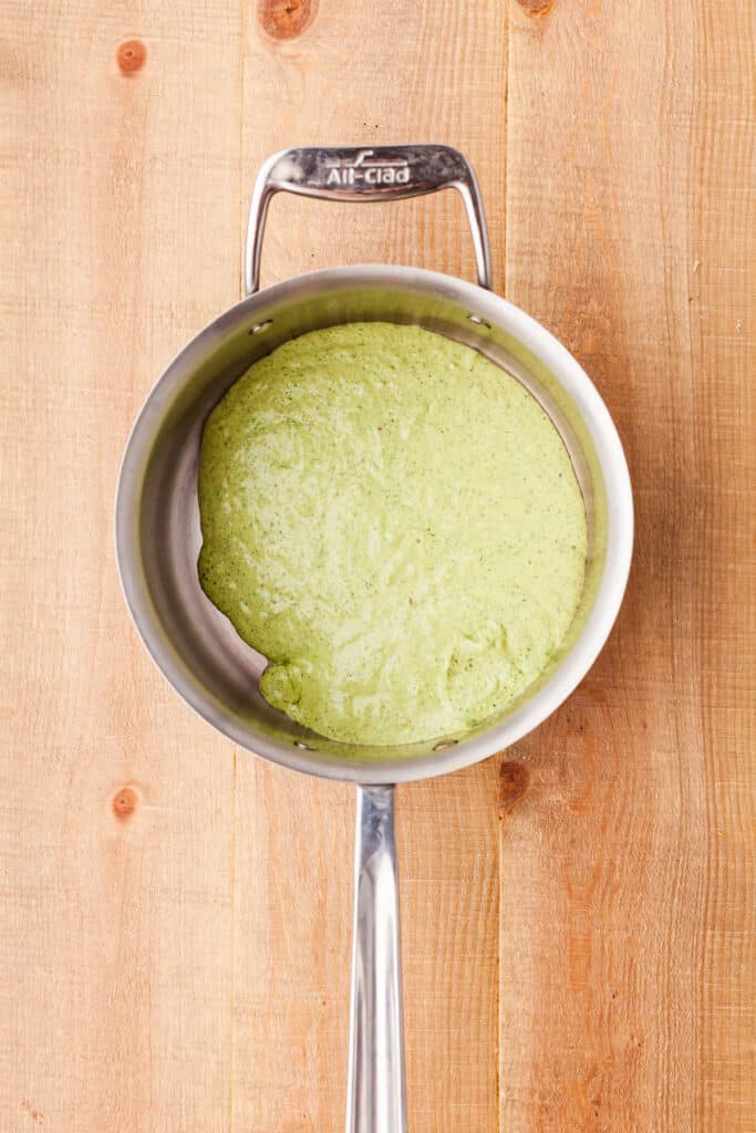 protein pesto sauce in a sauce pan on wooden countertop.