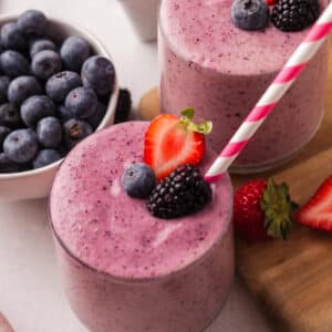 berry fertility smoothie in a glass with straw and decorative berries.