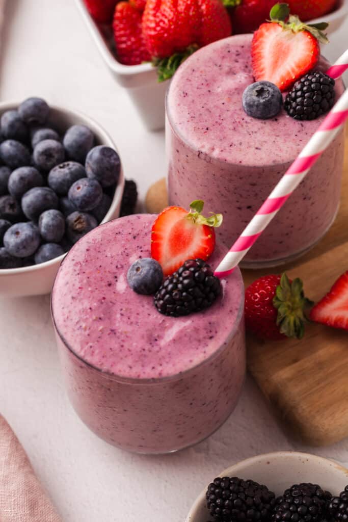 berry fertility smoothie in a glass with straw and decorative berries.