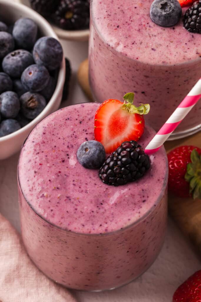 berry fertility smoothies in a glass with straw and decorative berries.