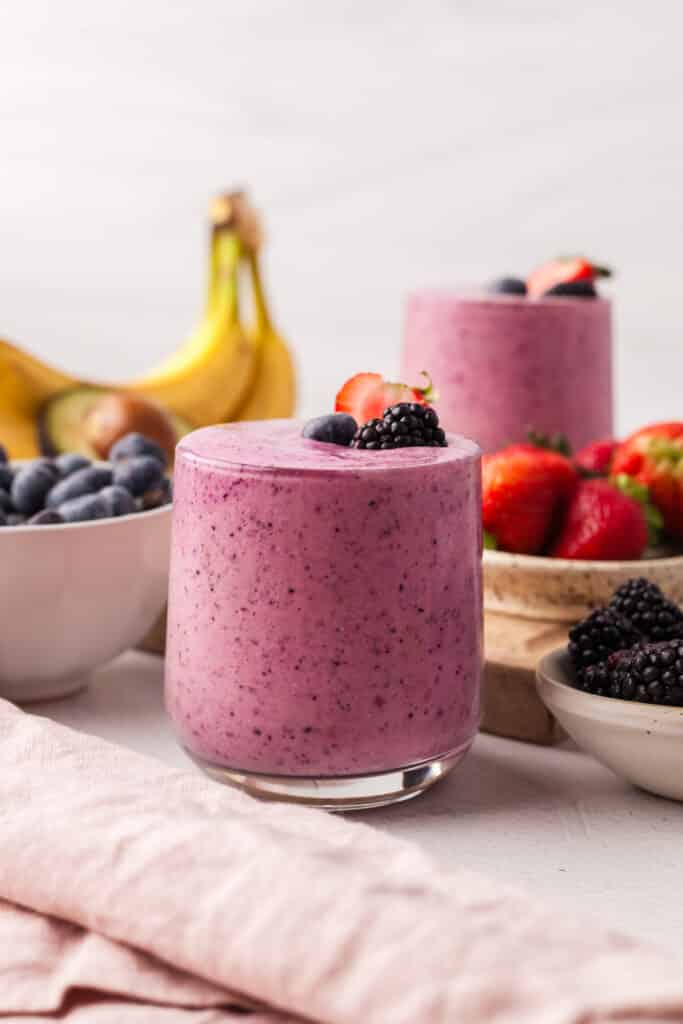 berry fertility smoothie in a glass with ingredients surrounding it.