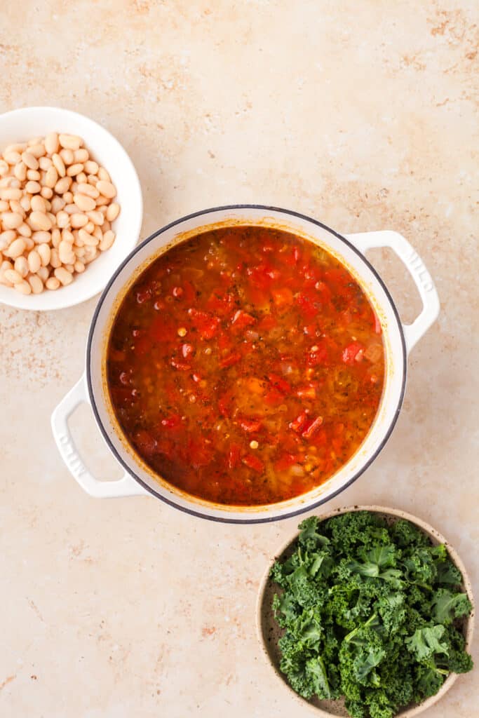 process shot of white bean and lentil soup being made with next ingredients surrounding it.