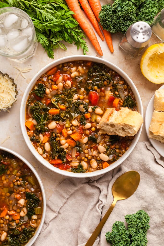 lentil and white bean soup in a white bowl with bread piece.