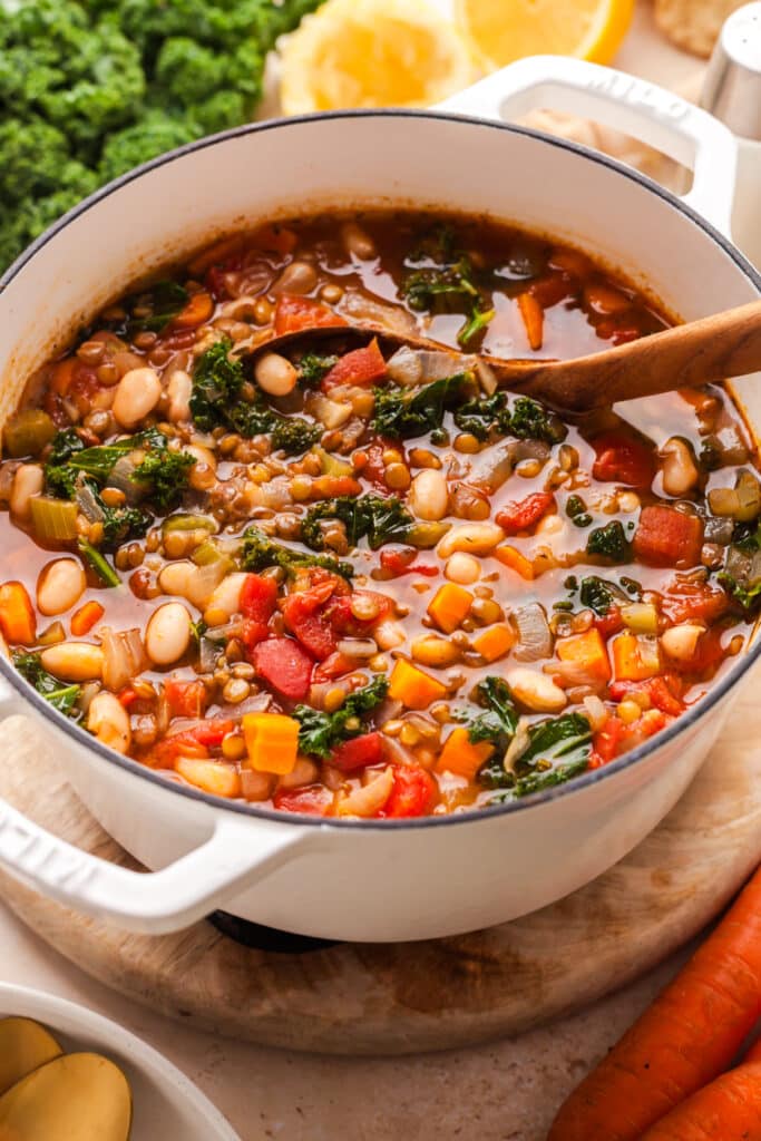 lentil and white bean soup with wooden soup inserted in a stockpot.