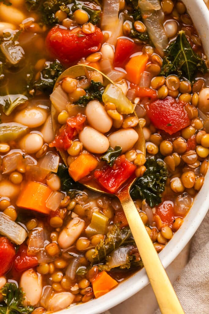 closeup of lentil and bean soup on a golden spoon.