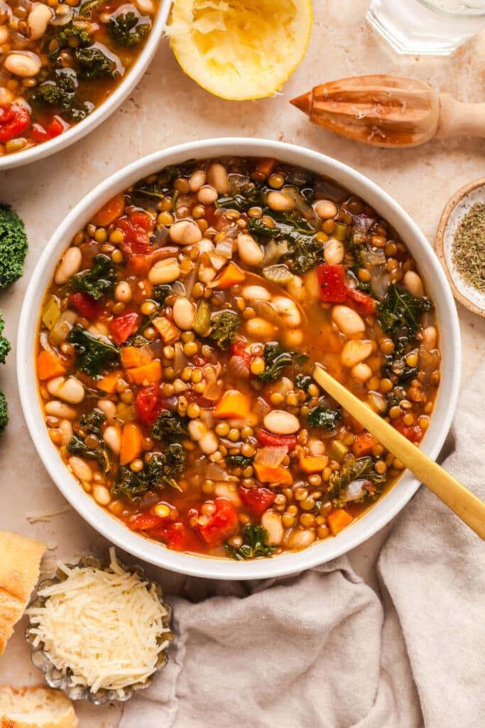 lentil and white bean soup in a white bowl with gold spoon inserted.