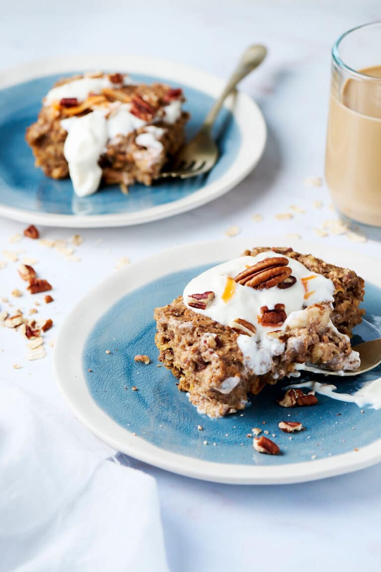 two blue plates with slices of carrot cake baked oats and frosting on them.