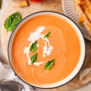 high protein tomato soup topped with basil leaves and cream in a bowl.
