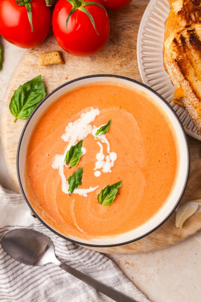 high protein tomato soup topped with basil leaves and cream in a bowl.