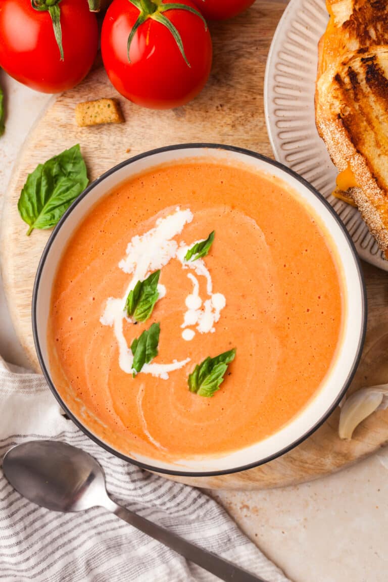 high protein tomato soup topped with basil leaves and cream in a bowl.