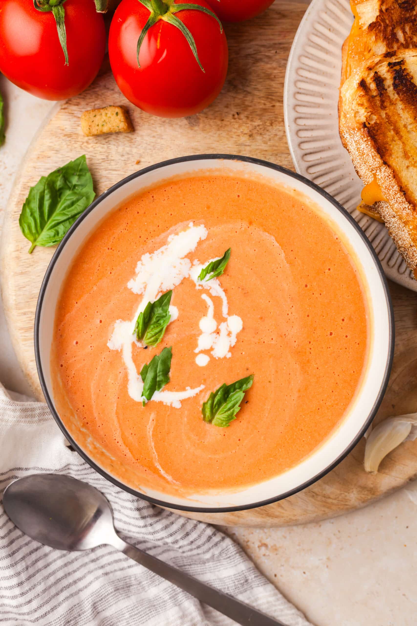 high protein tomato soup topped with basil leaves and cream in a bowl.