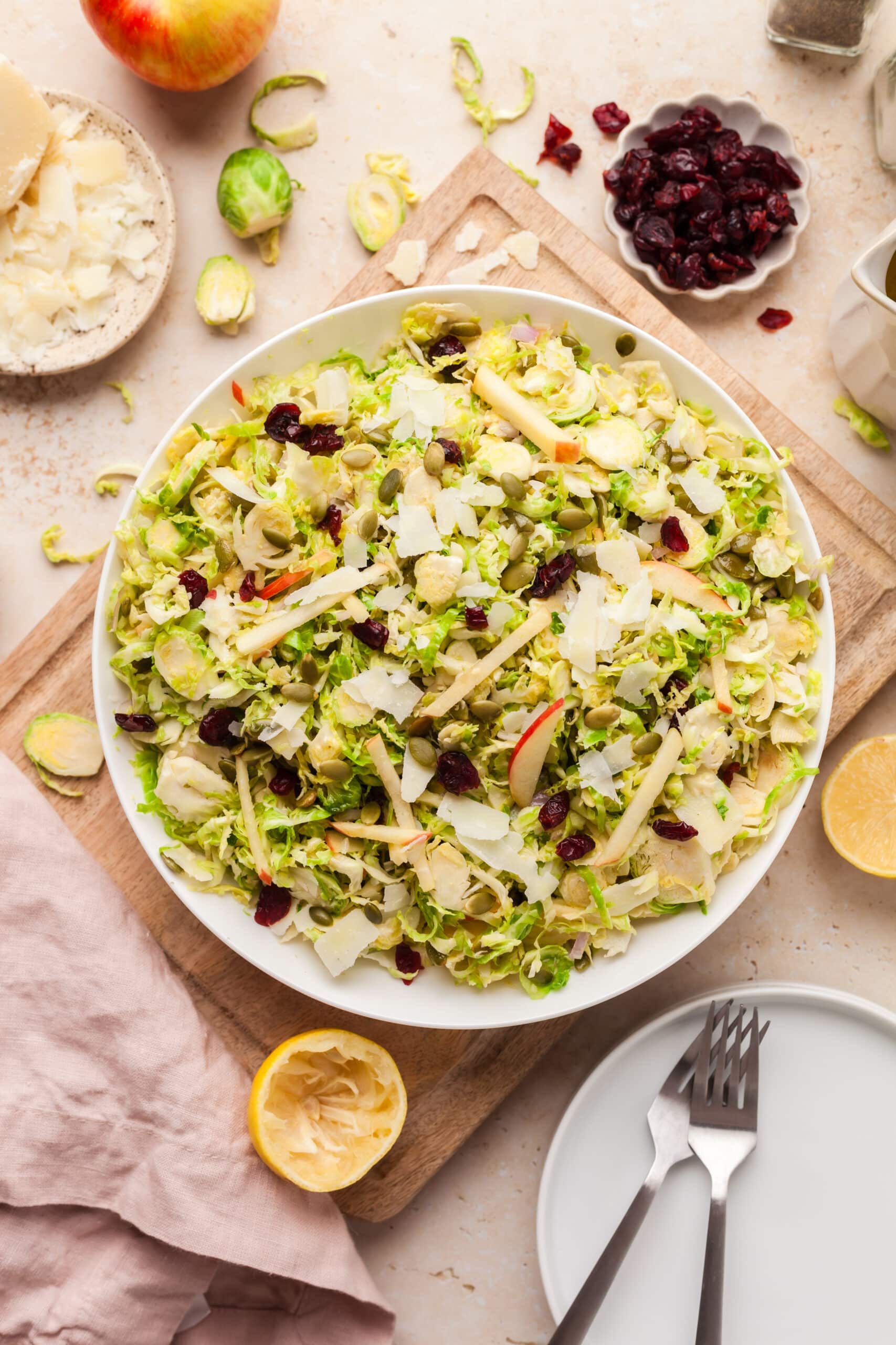 shaved brussels sprout salad on a white plate with ingredients surrounding it.