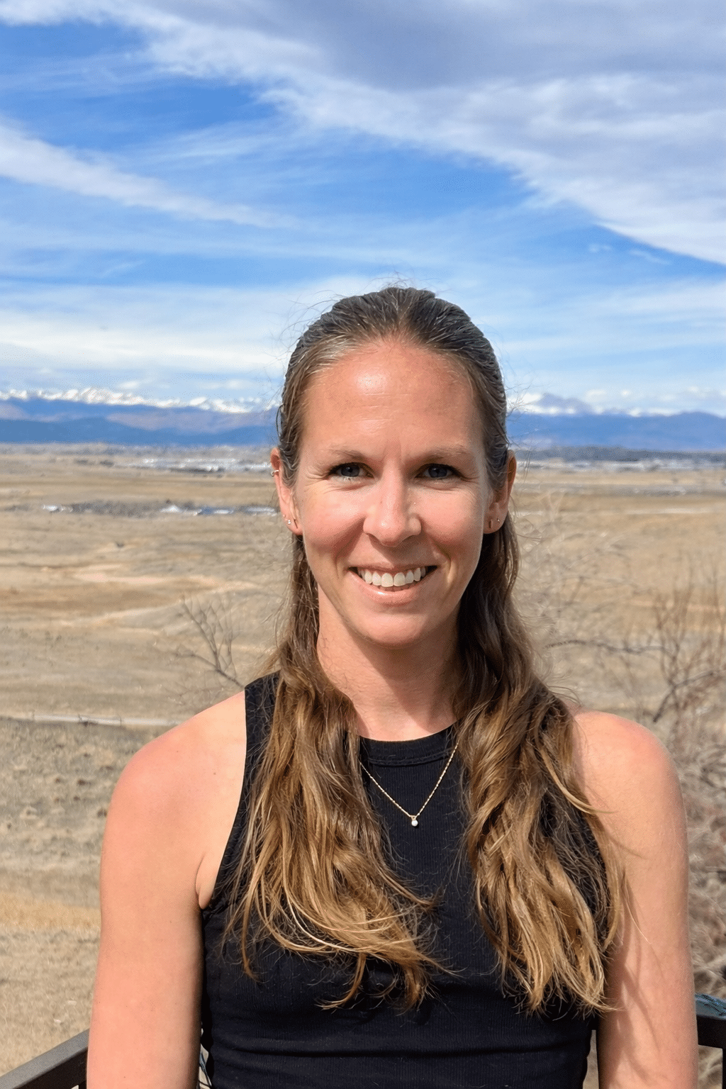 woman smiling at camera with picturesque background.