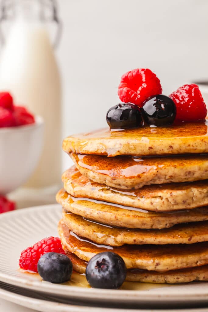 stack of pcos friendly pancakes with berries and syrup.
