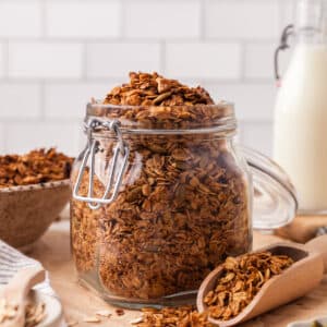 pcos friendly granola in glass jar with wooden scoop next to it.