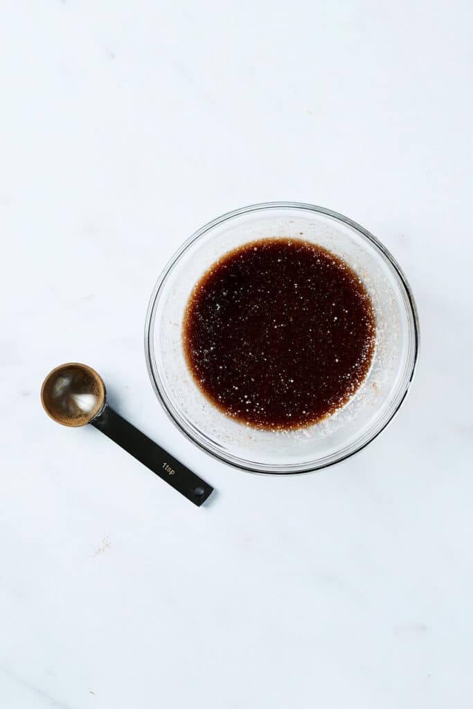 marinade in glass bowl with measuring spoon next to it.