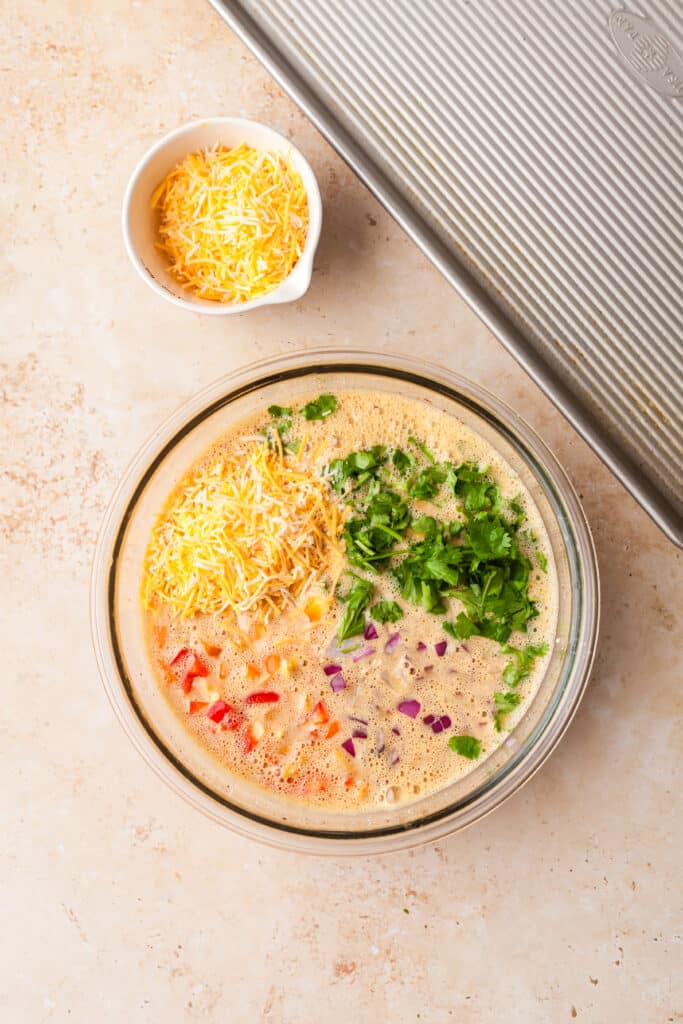 veggies and raw egg mixture in a glass bowl before mixed together.