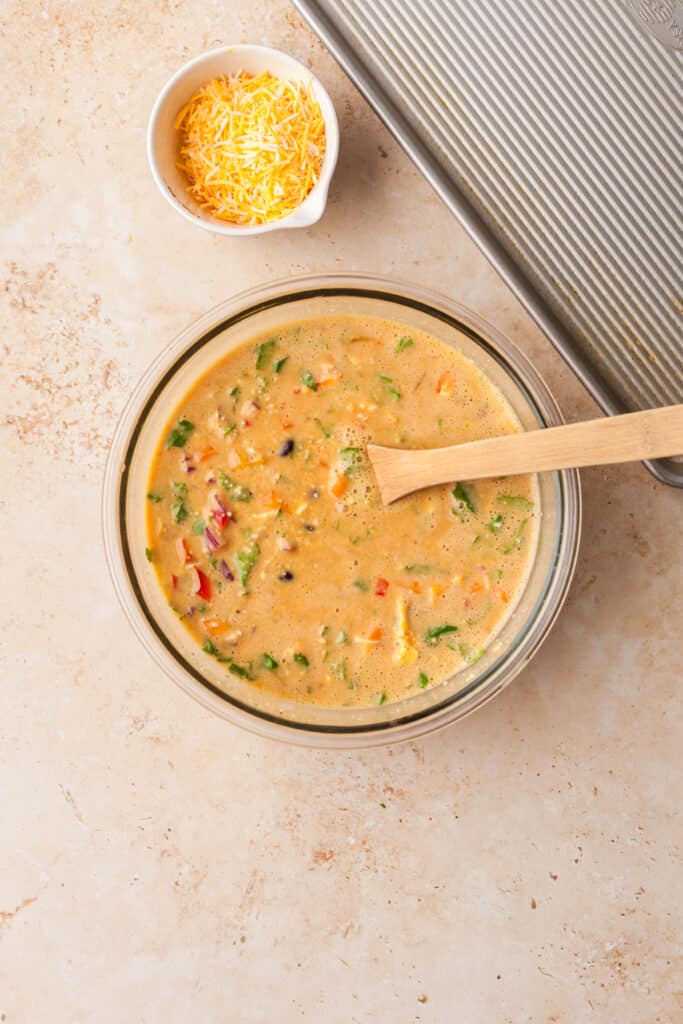 veggies and raw egg mixture in a glass bowl mixed together.