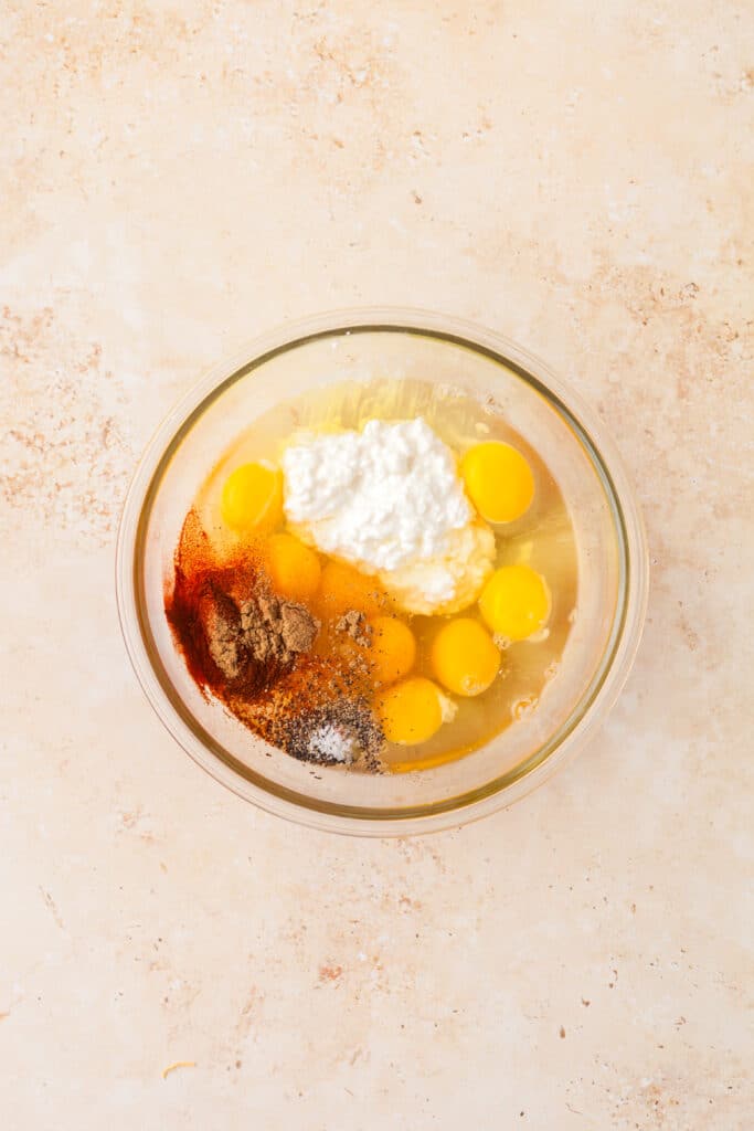 raw eggs and other ingredients in a glass bowl.