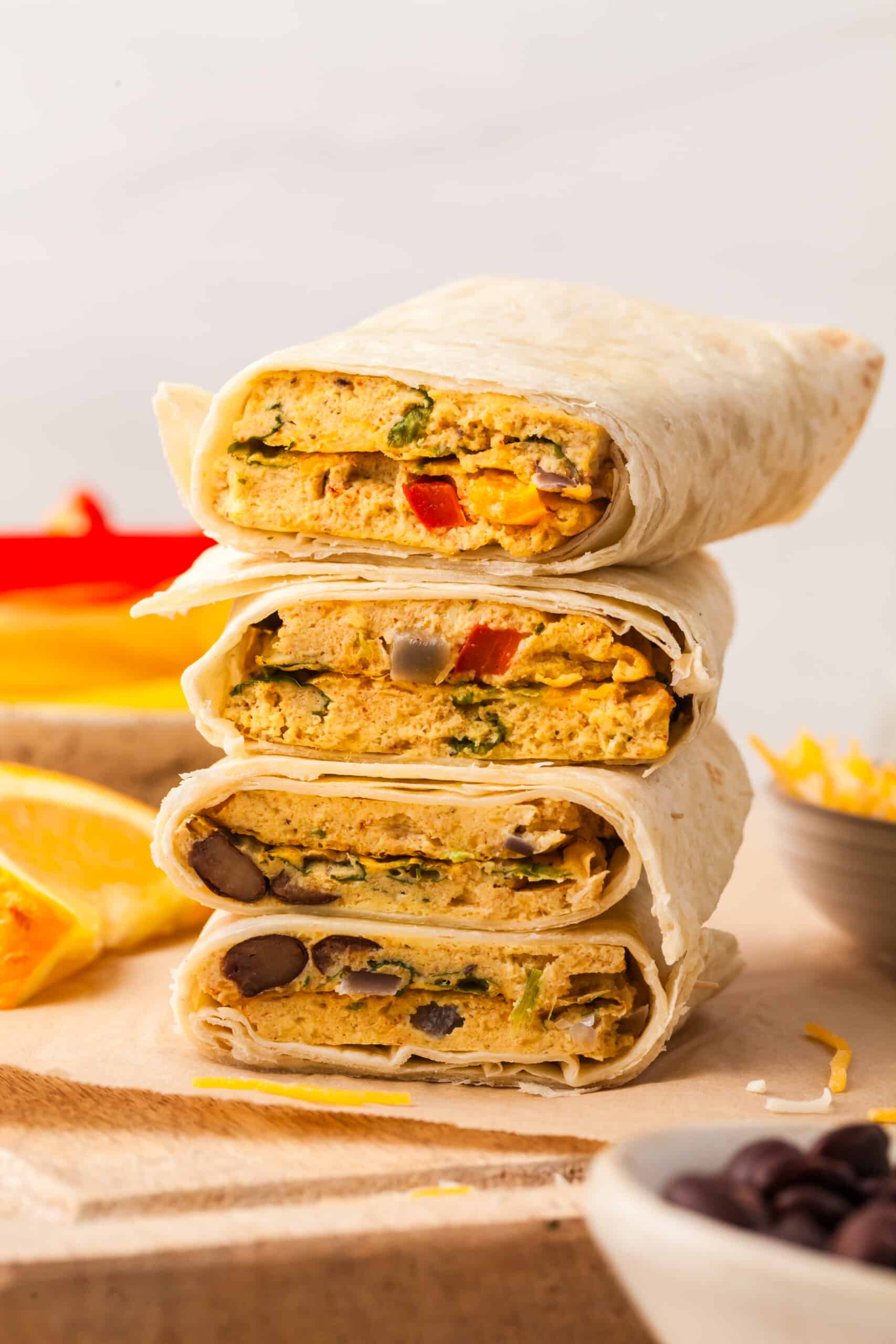 sheet pan egg burritos in tortillas stacked on top of each other.