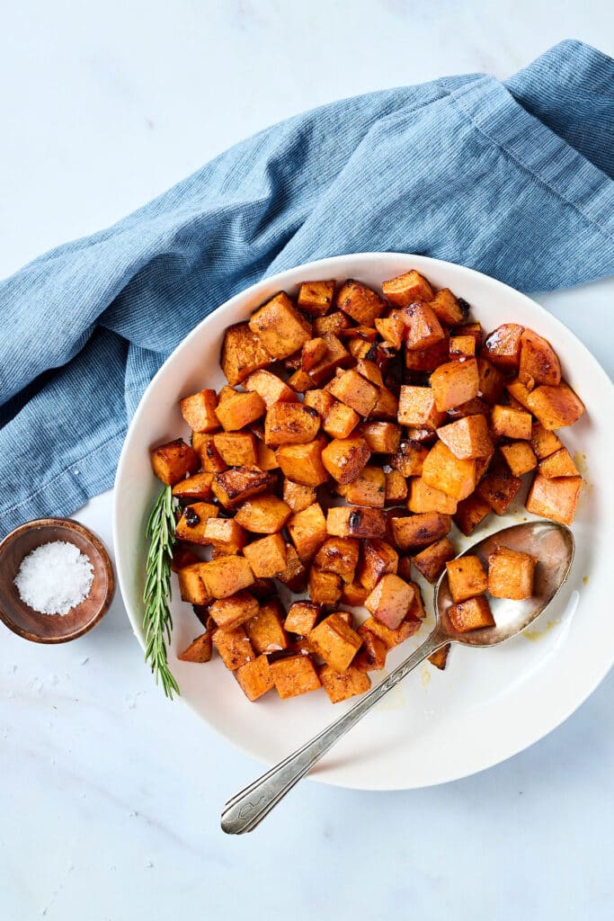 roasted sweet potatoes in white bowl with spoon.