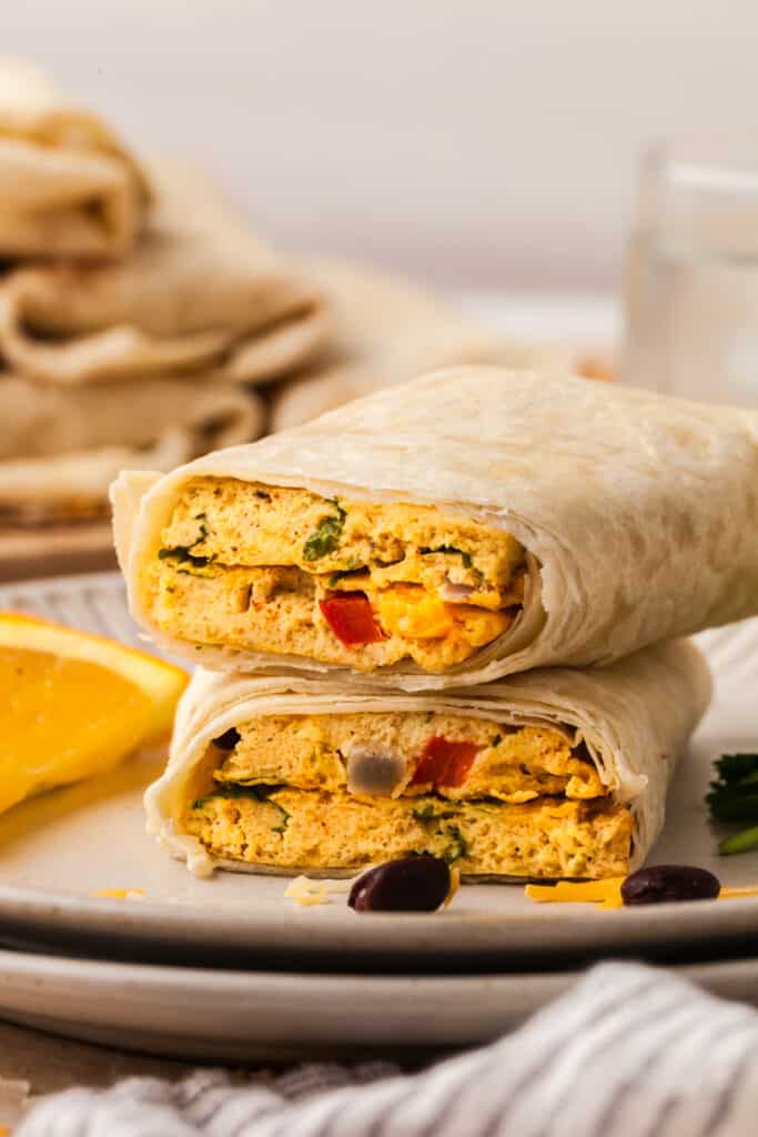 sheet pan egg burritos in tortillas stacked on top of each other.