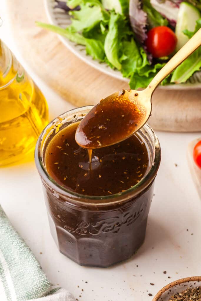 pcos friendly maple balsamic dressing In a mason jar with a spoonful on top.