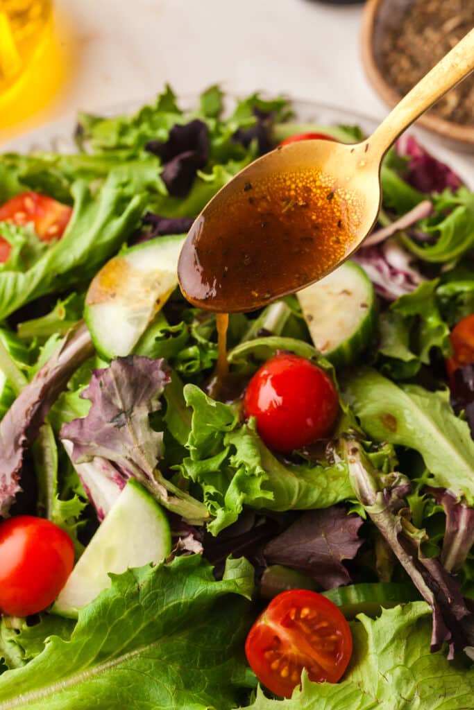 pcos friendly salad dressing being spooned over a green salad.