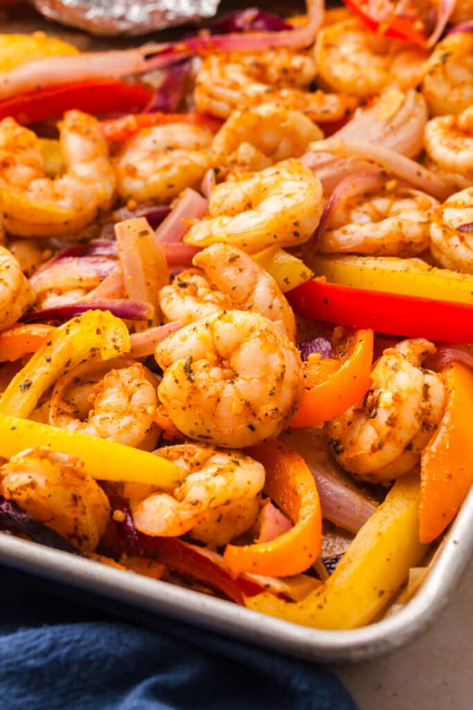 shrimp fajitas and bell peppers on a baking sheet close up.