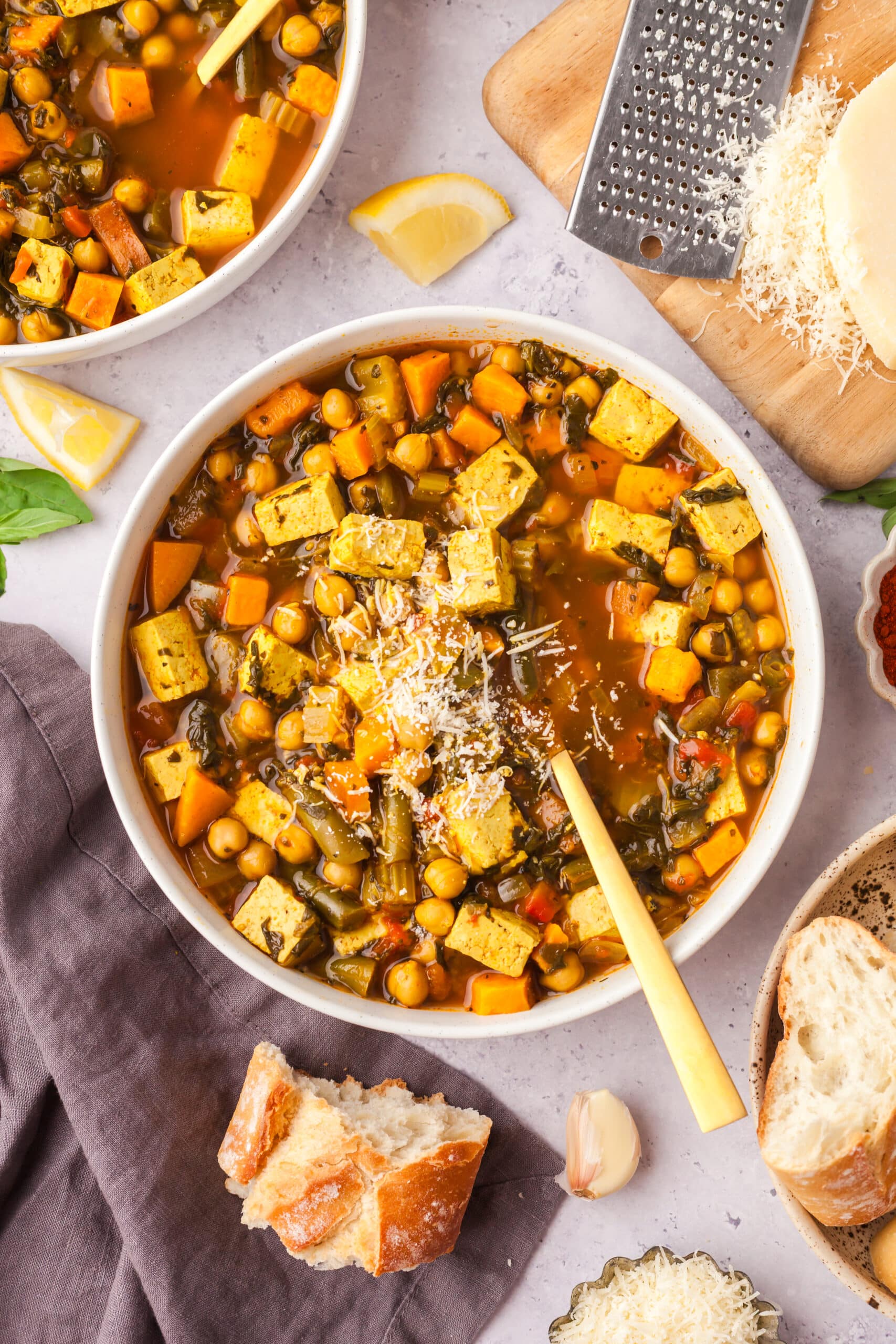 golden chickpea and veggie soup in a bowl with spoon inserted.