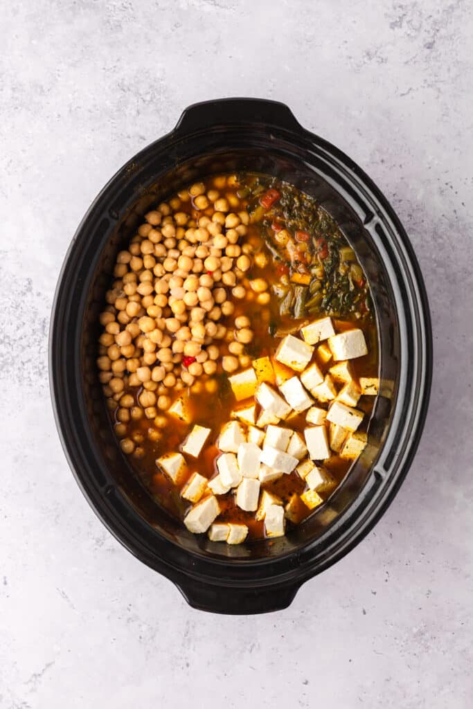 process shots of a golden chickpea and veggie soup in a crockpot.