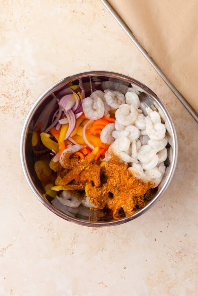 shrimp fajita ingredients in a large stainless steel bowl.