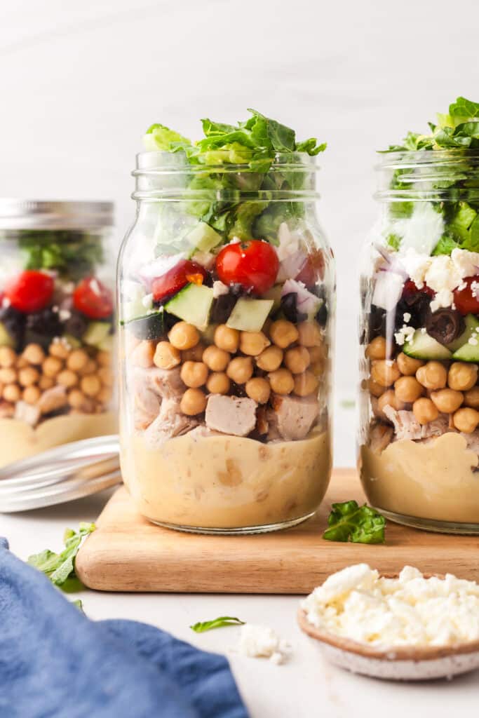 mason jar salads on a wood cutting board.