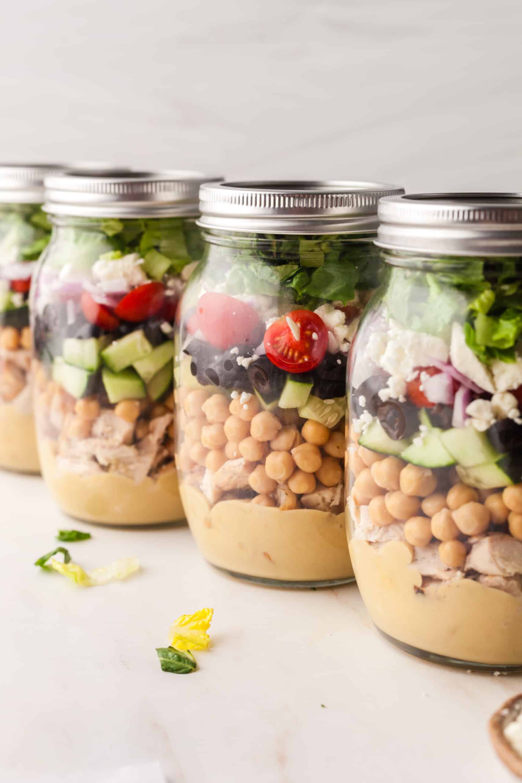 mason jar salads lined up on a white countertop.